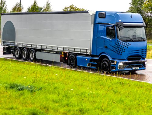 Large blue truck driving on a wet road after rain, showcasing strength, innovation, and the future of professional logistics and transport.